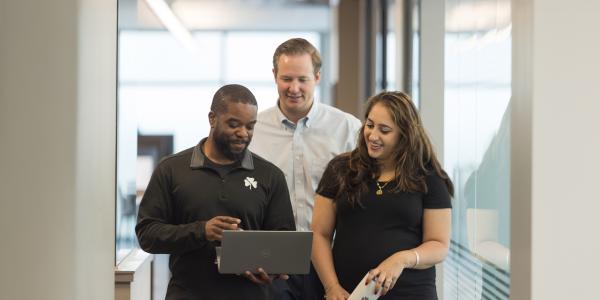 Three employees walking and talking